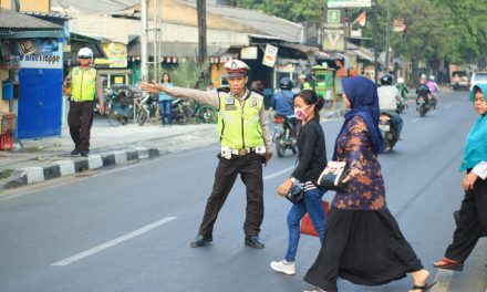 Jaga Keselamatan dan Kelancaran di Jalan Raya, Anggota Lantas Polsek Jatiuwung Layani Penyeberang Jalan